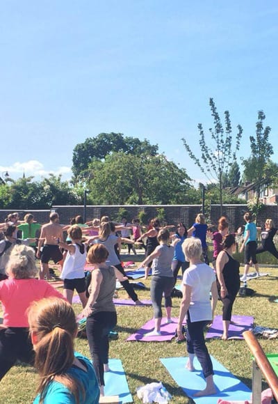 Large group doing outdoor yoga classes image 3